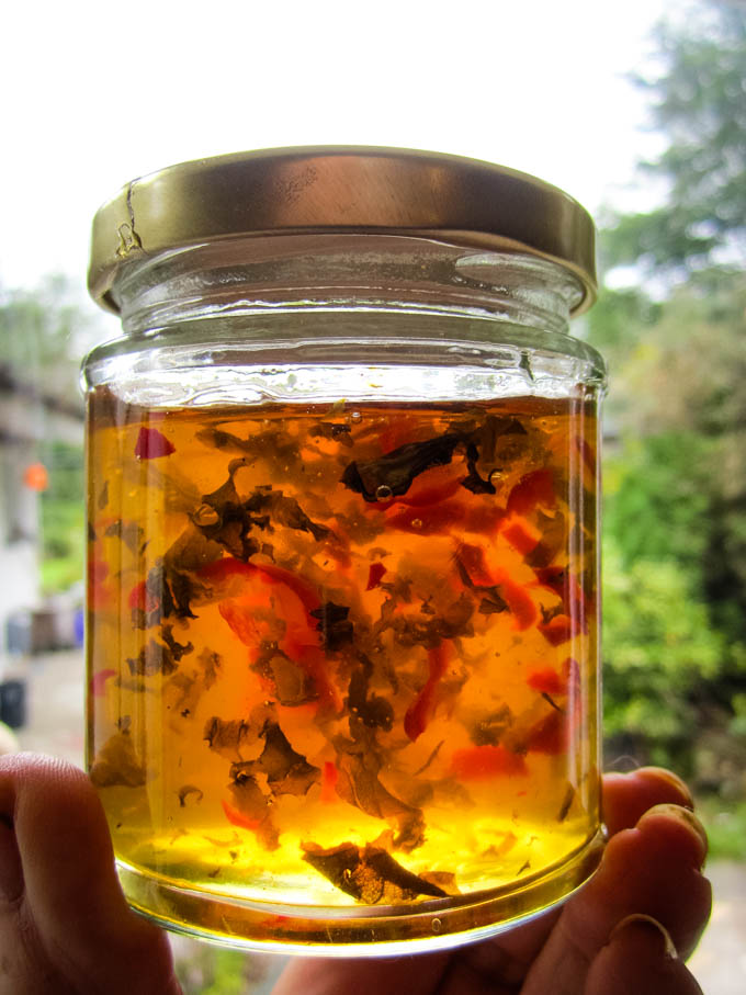 chilli and basil jelly in jar being held up to light