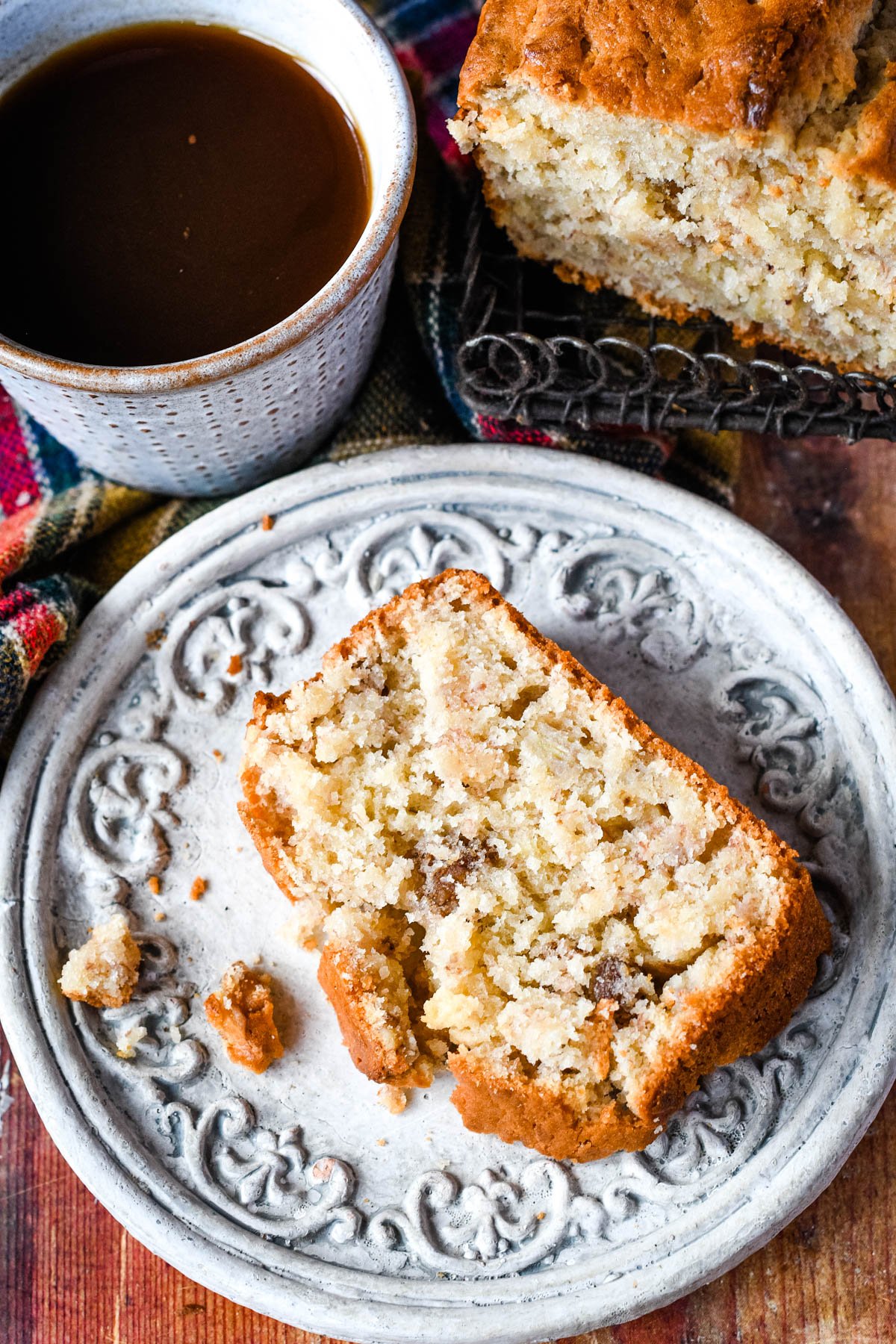 Slilce of banana bread on saucer with coffee beside it