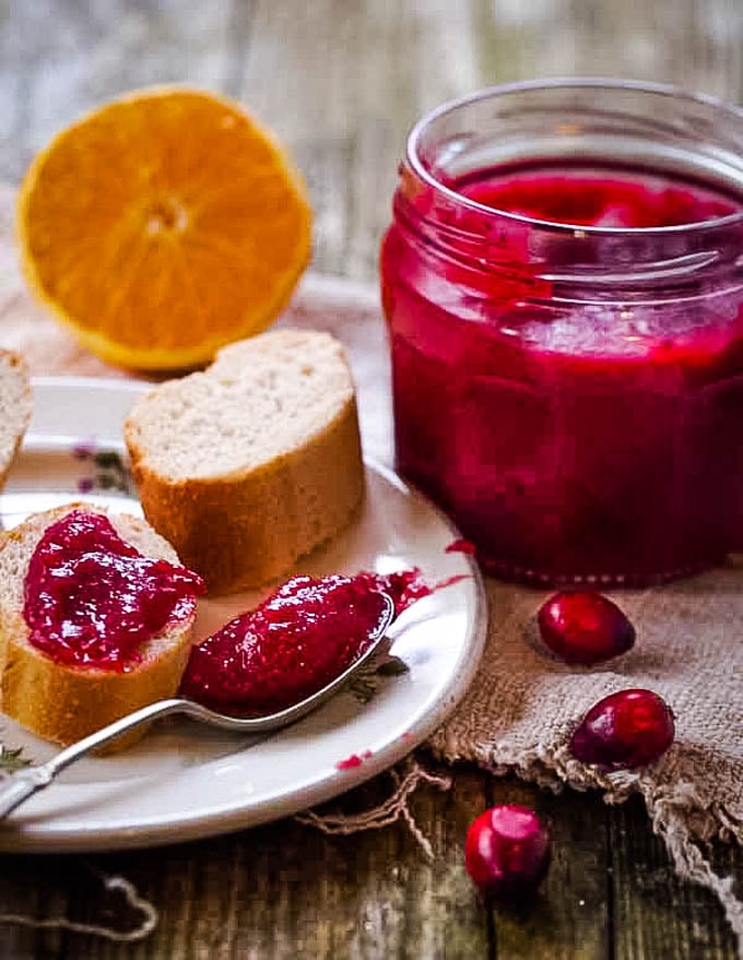 long shot of jar or curd with orange in background and spoon in front