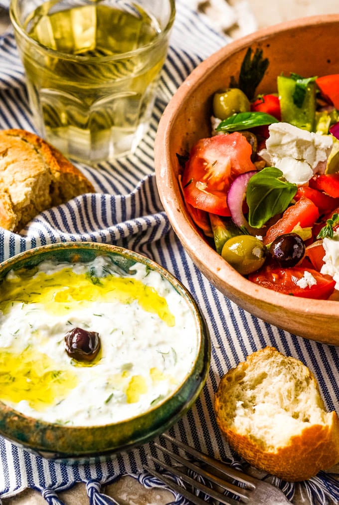 tzatziki with greek salad and wine in background