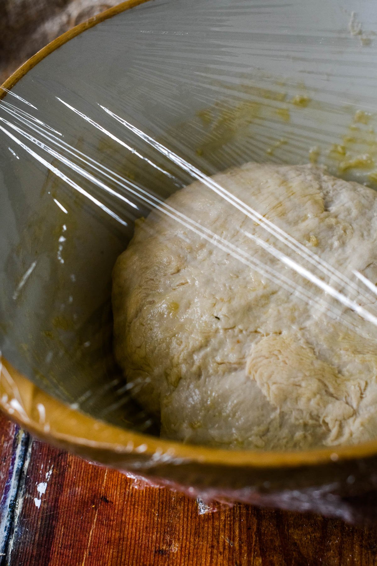 focaccia dough in a bowl with cling film on top
