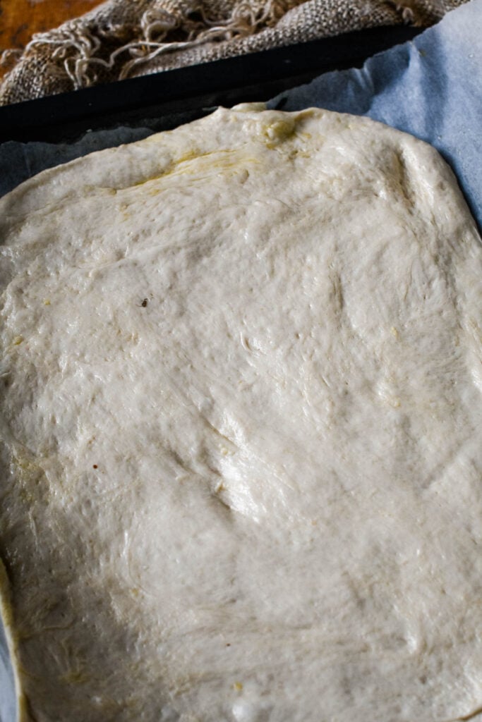 focaccia dough flattened out on baking tray