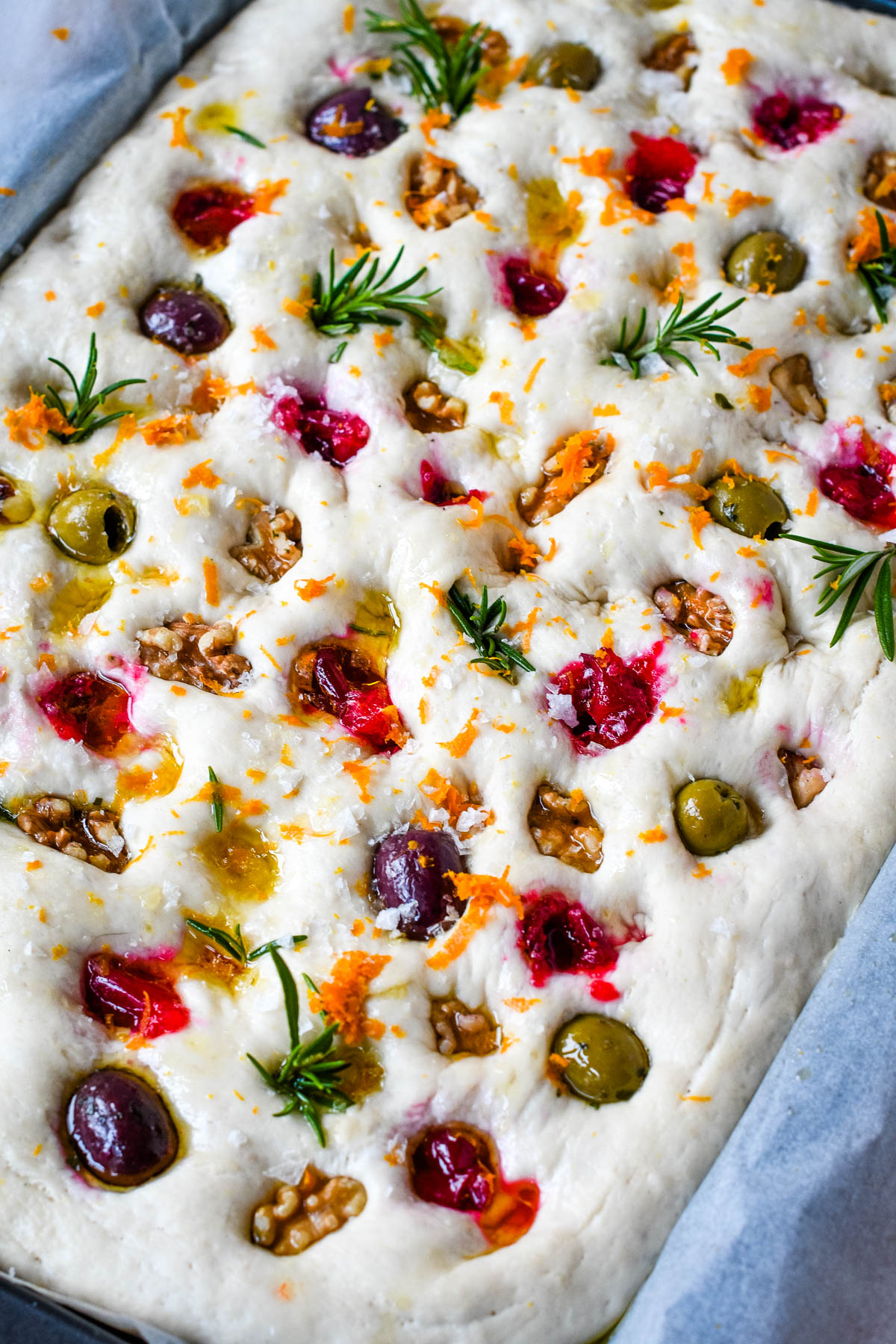 festive focaccia dough ready to go into the oven with toppings on it