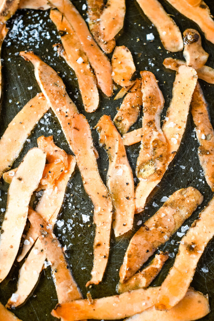 sweet potato peelings on oven tray wiyh salt and pepper