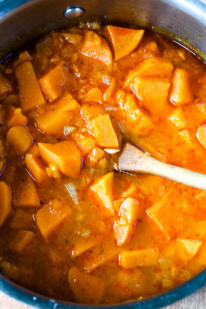 stock added to pan with wooden spoon