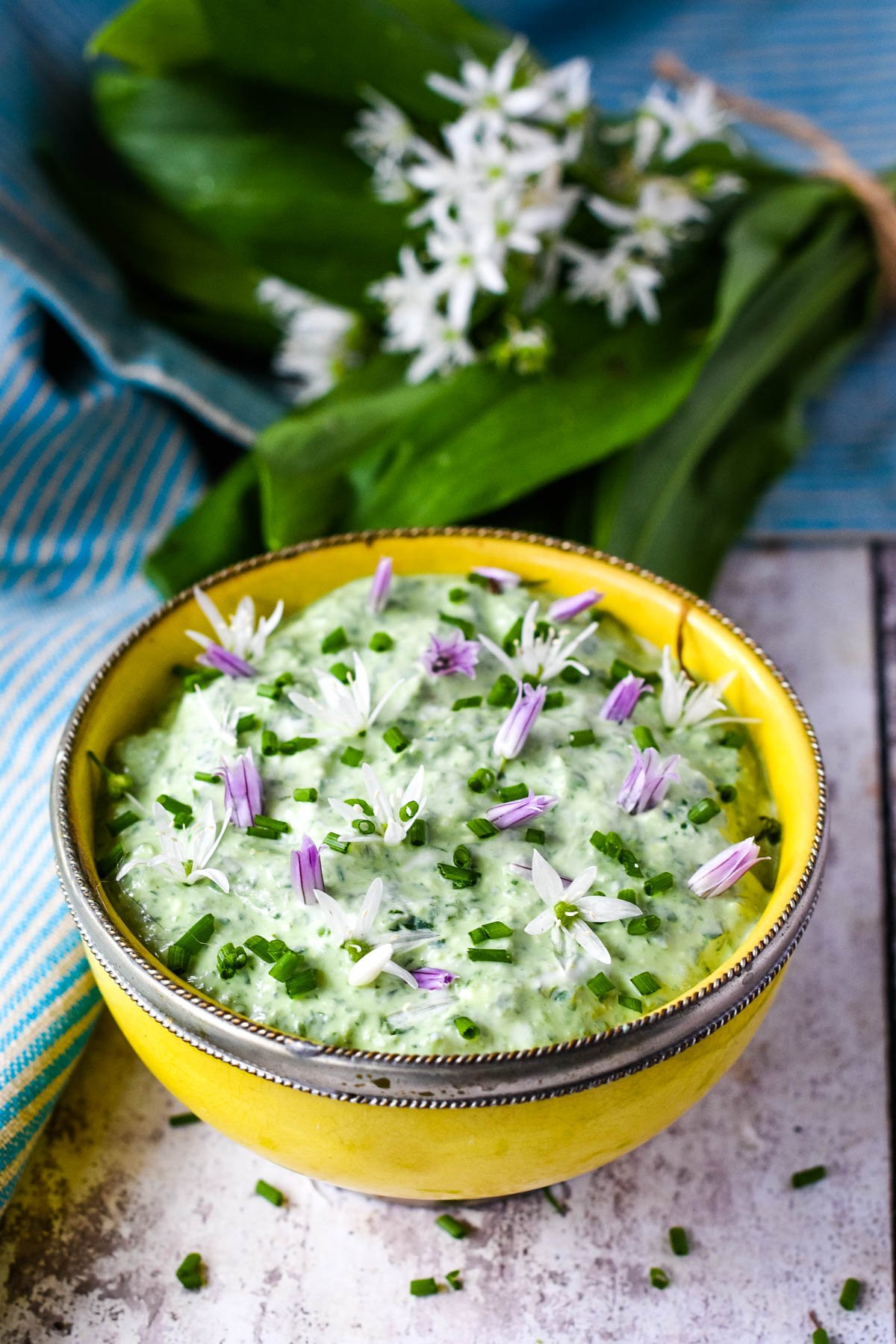 wild garlic dip in yellow bowl with wild garlic behind
