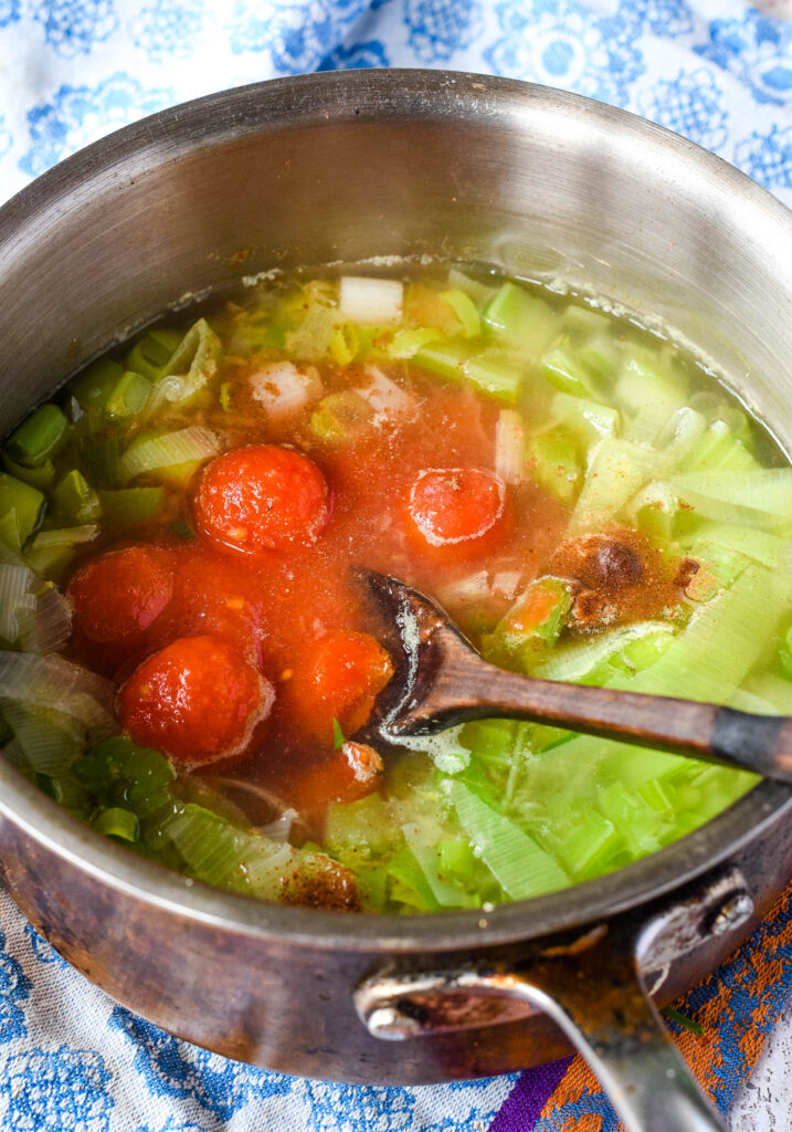 tinned tomatoes added to the soup in the pan