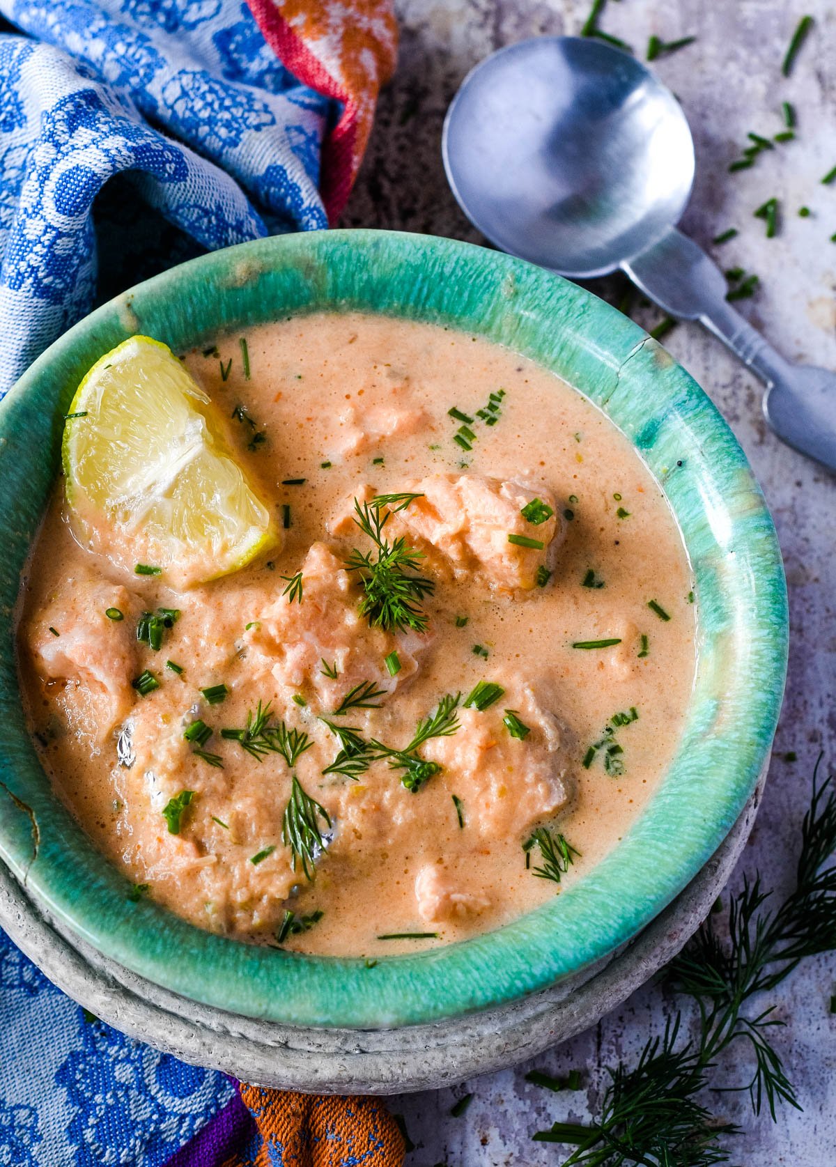 top down shot of bowl of salmon soup with spoon above