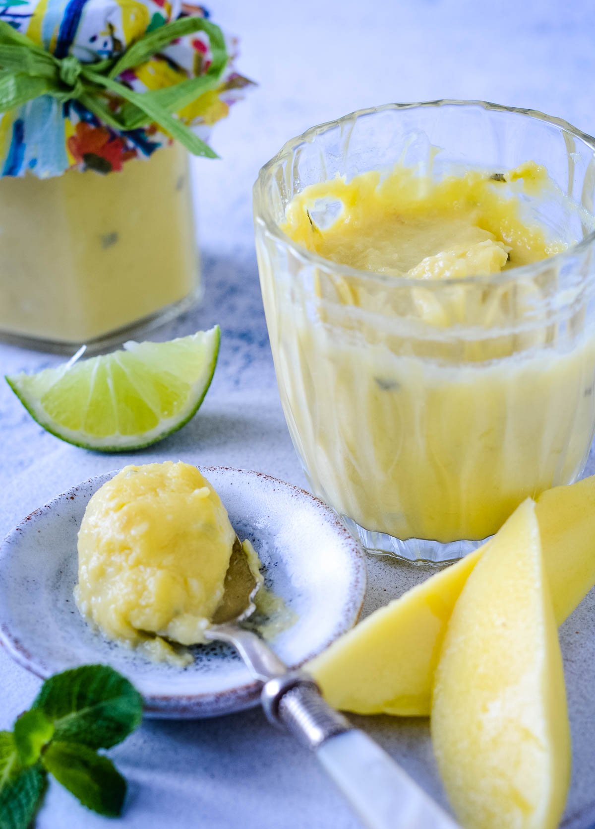 close up of spoonful of mango curd with jar at the side
