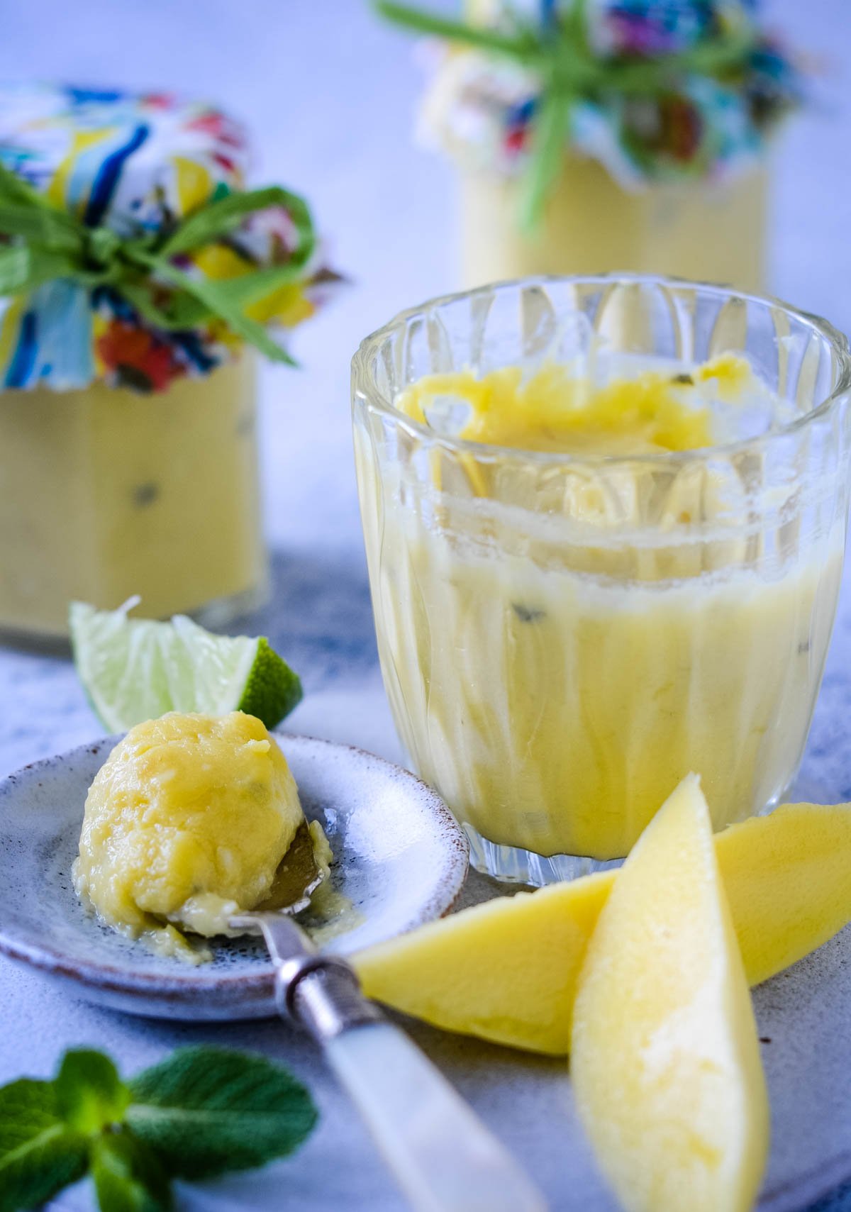spoonful of mango and lime curd with jar of curd at side and other jars behind