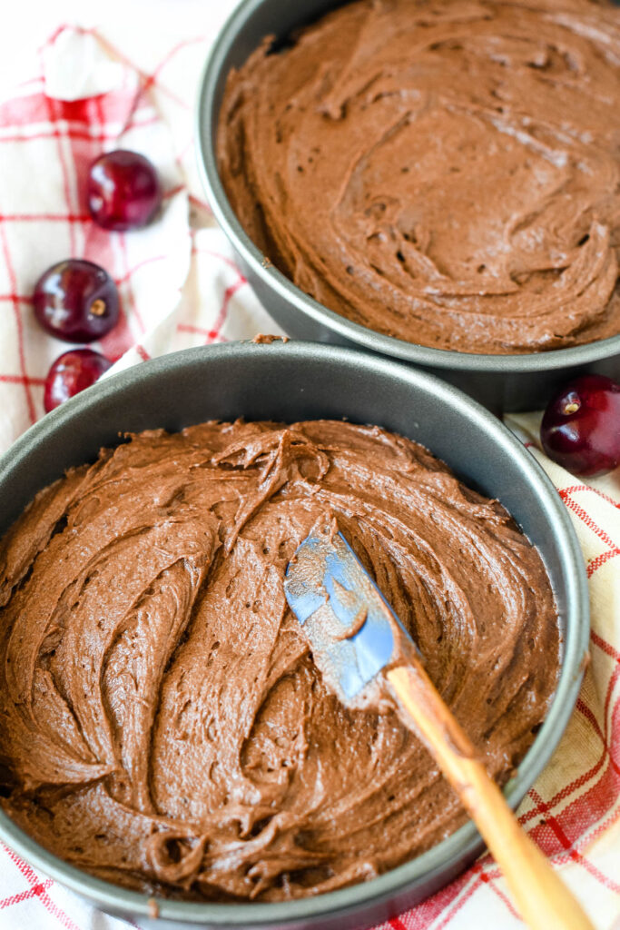 spreading the chocolate cake batter into two cake tins