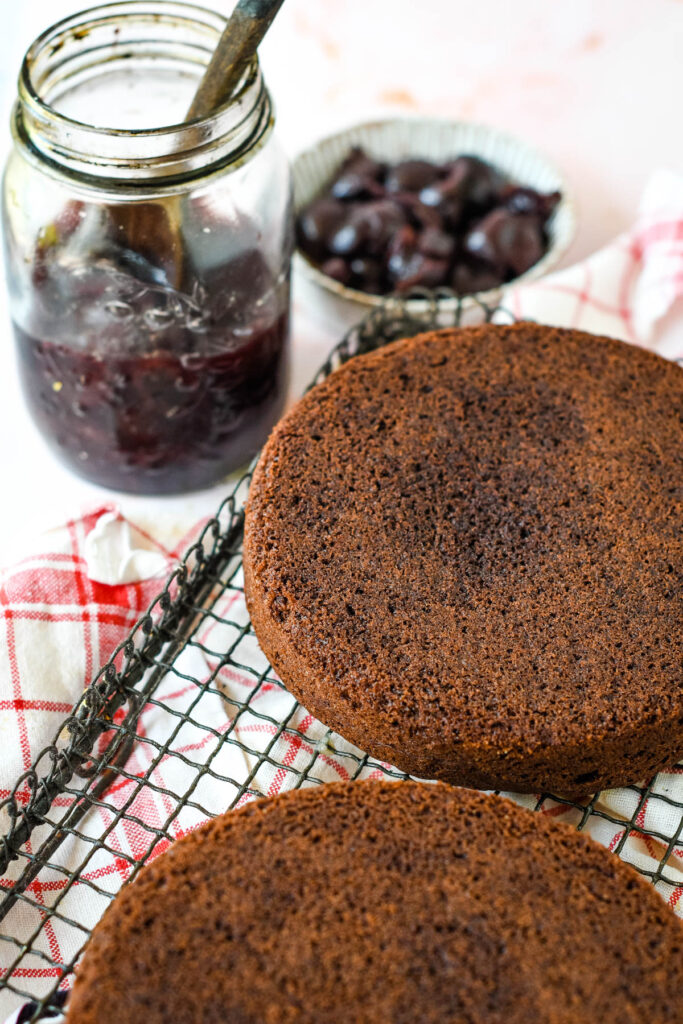 2 baked sponge cakes with jar of cherries behind