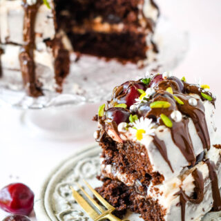 slice of cherry chocolate cake with cake fork and remaining cake behind