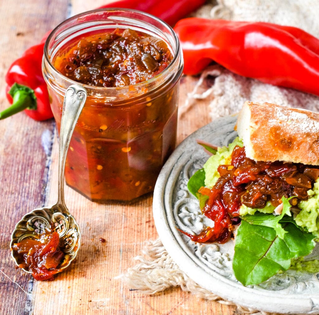 red pepper chutney in jar with sandwich