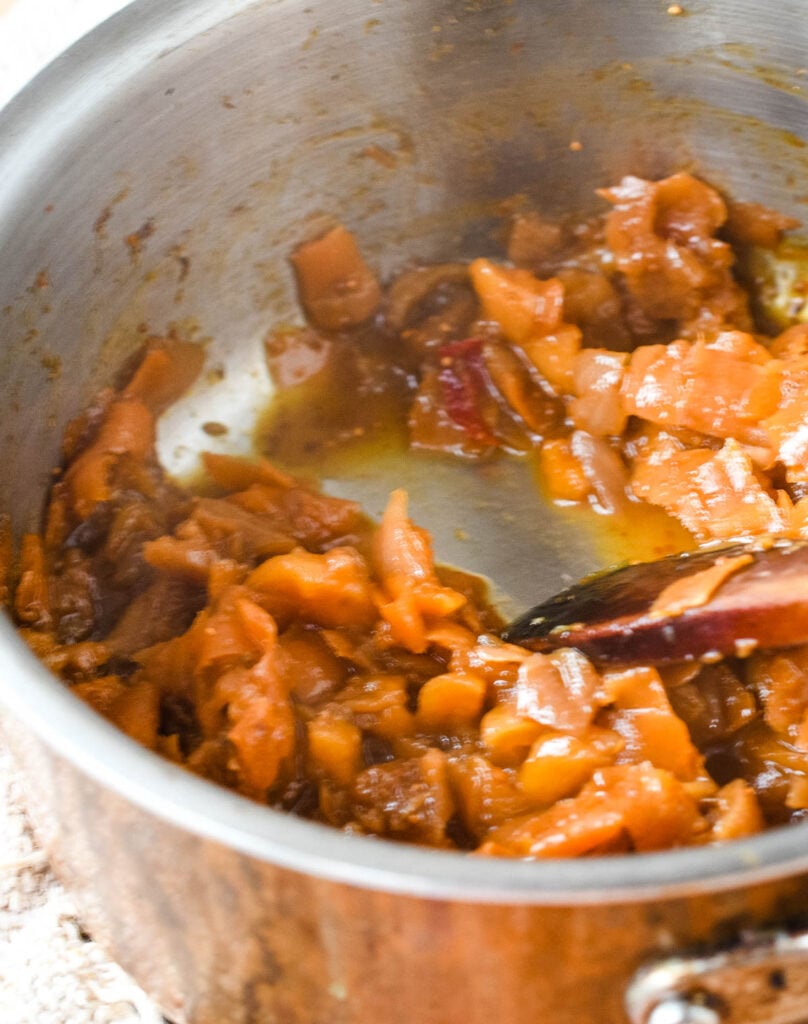 testing that the chutney is ready in the pan with wooden spoon