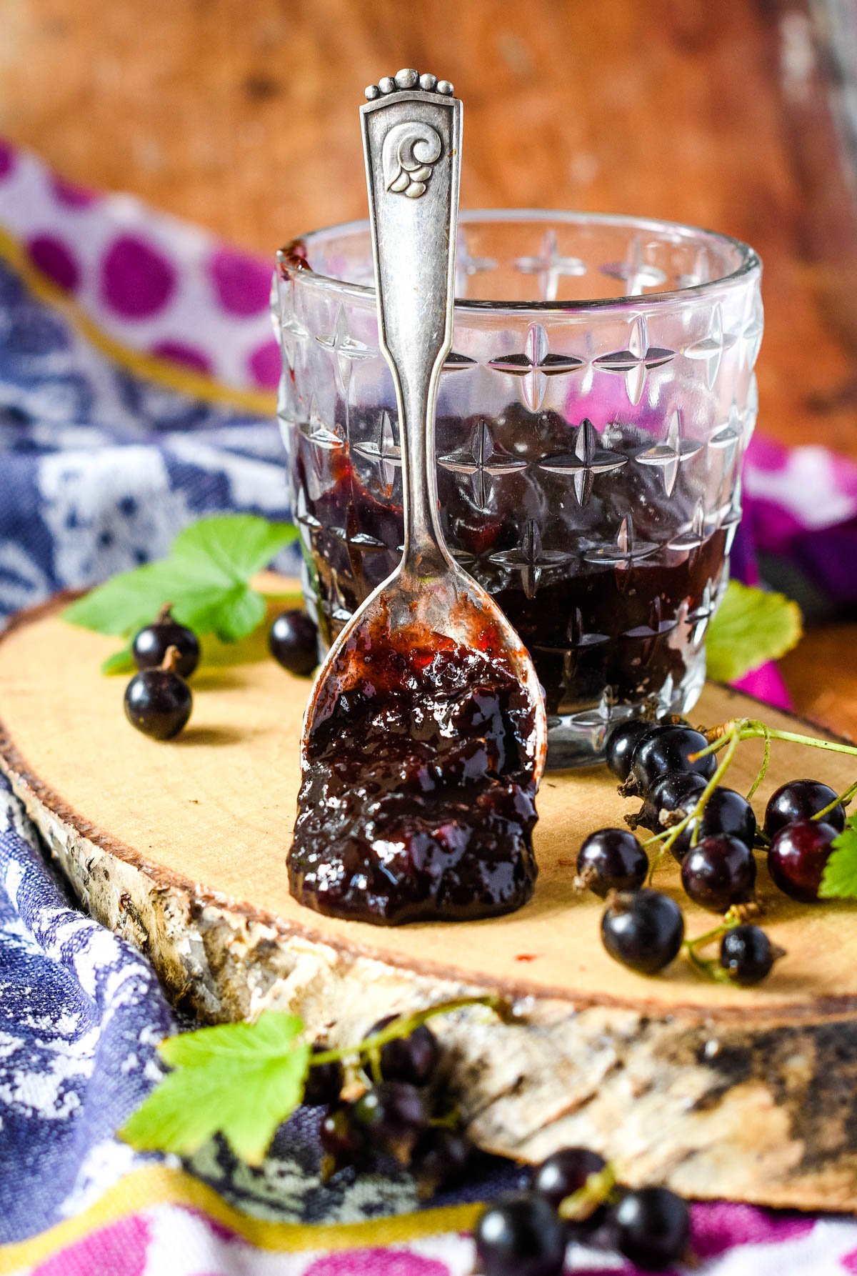 Blackcurrant chutney in jar on log with blackcurrants