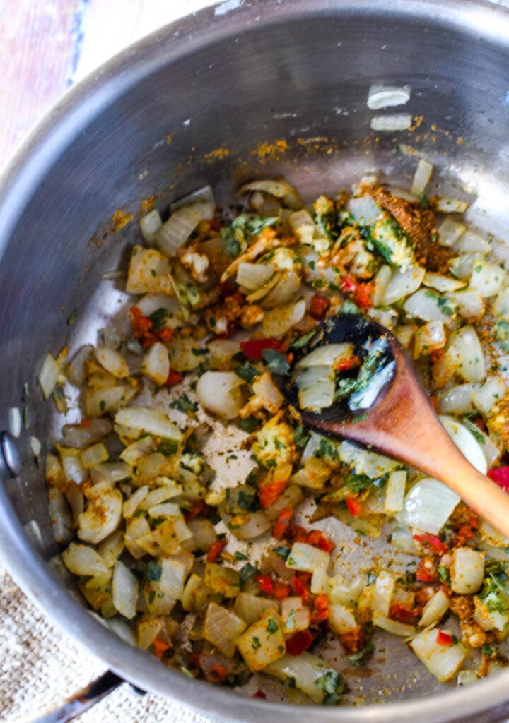 cooking the onion with spices in pan with wooden spoon