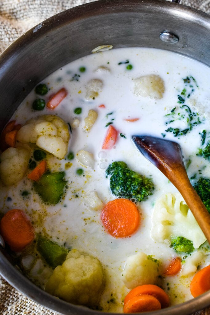 adding coconut milk and vegetables to the pan