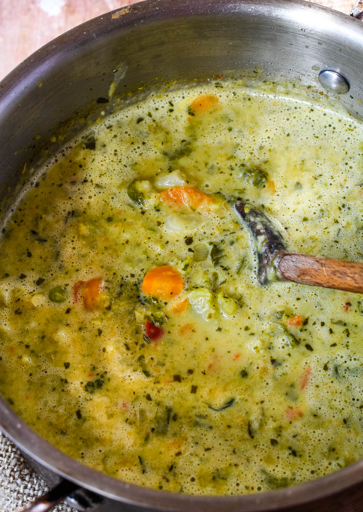 curried vegetable soup in pan with wooden spoon