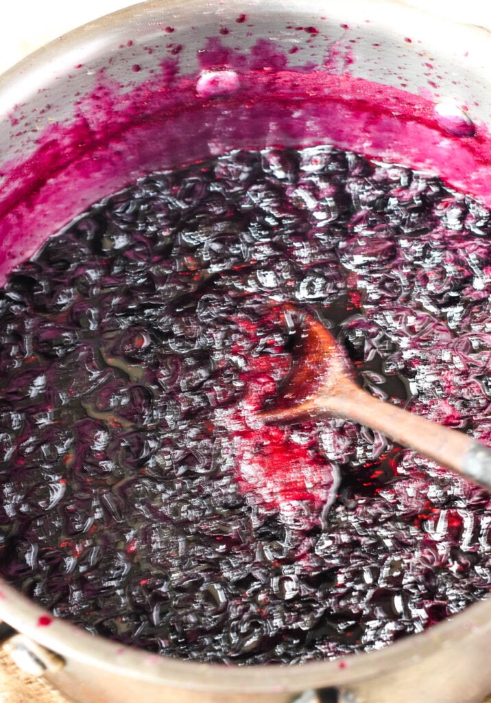 the blueberry jam cooked in pan with wooden spoon