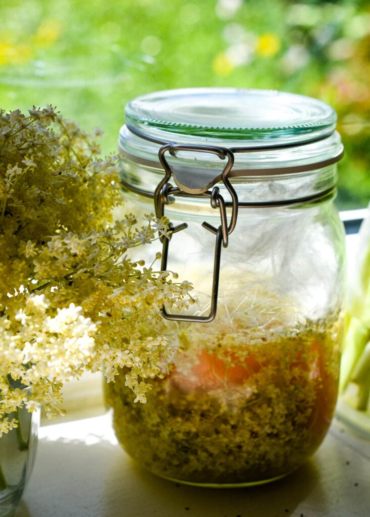 jar with elderflowers, vinegar and orange zest