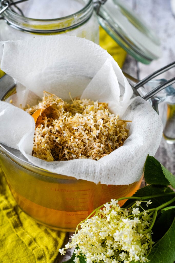 straining out the solids in a sieve over glass jug