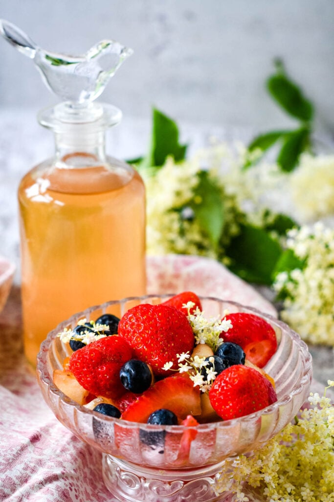 bottle of elderflowr vinegar with a fruit salad in front