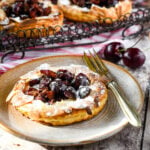 close up of cherry puff tart on plate with fork