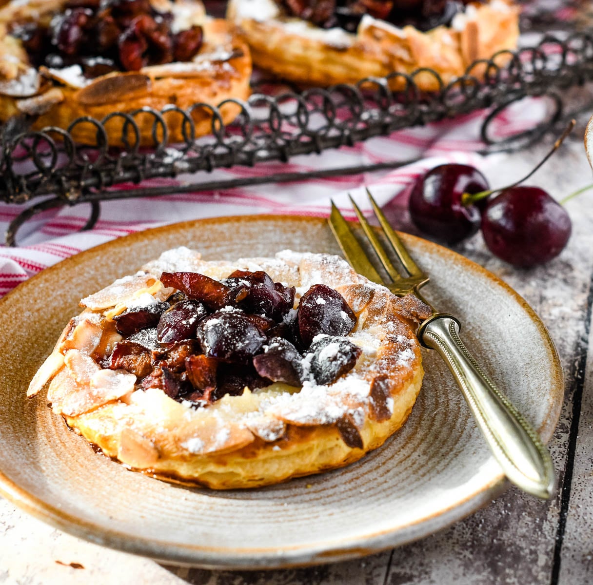 close up of cherry puff tart on plate with fork