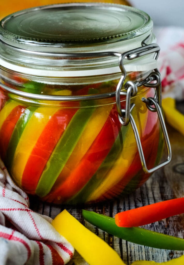 finished jar of mixed pickled peppers with a few slices beside the jar