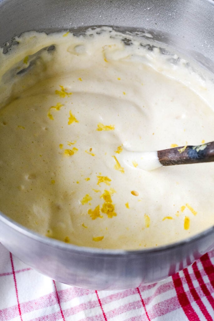 adding the lemon zest to cake batter in bowl