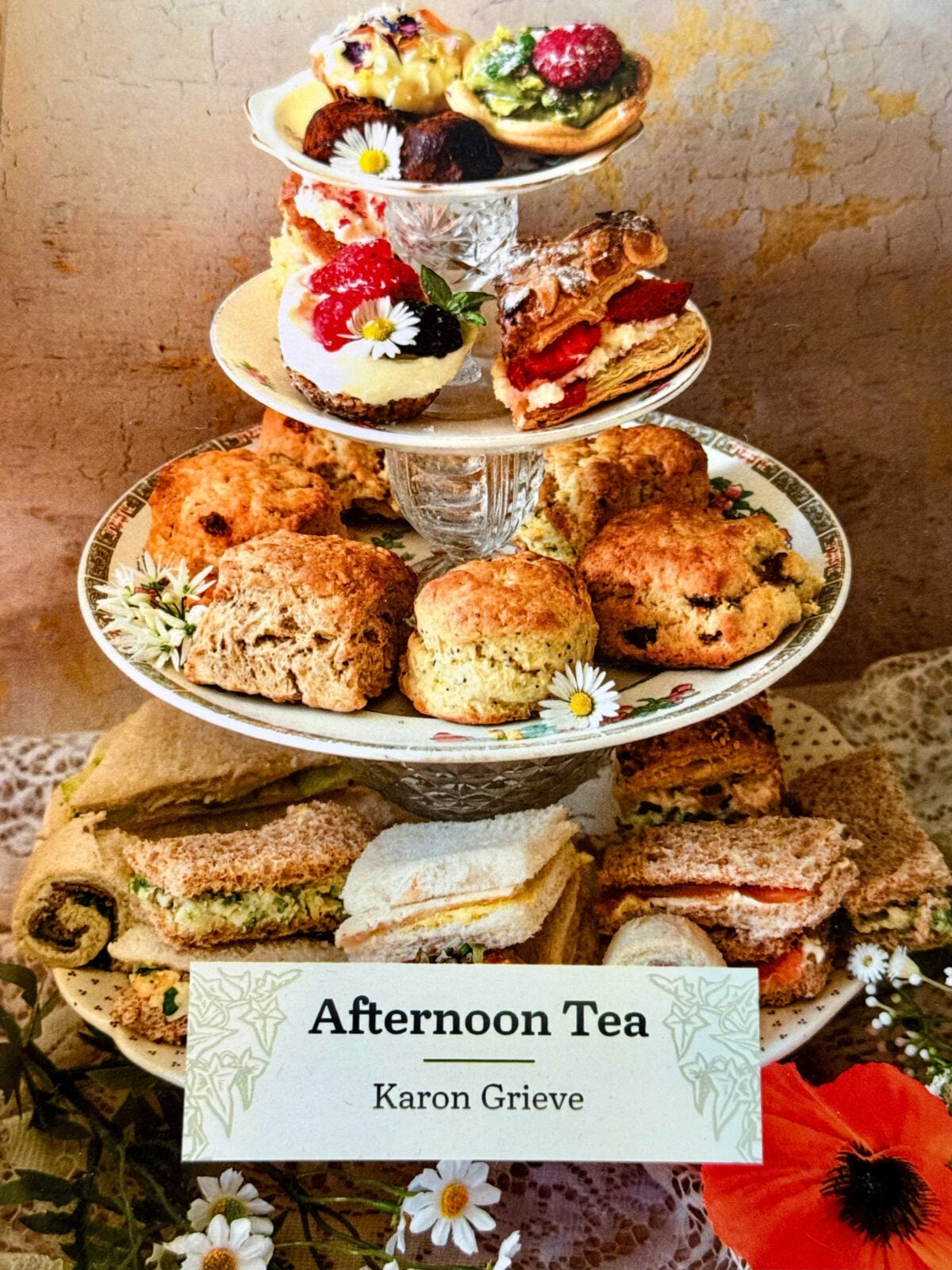 Cover of Karon Grieve’s Afternoon Tea book featuring a tiered stand filled with sandwiches, scones, cakes, and pastries.