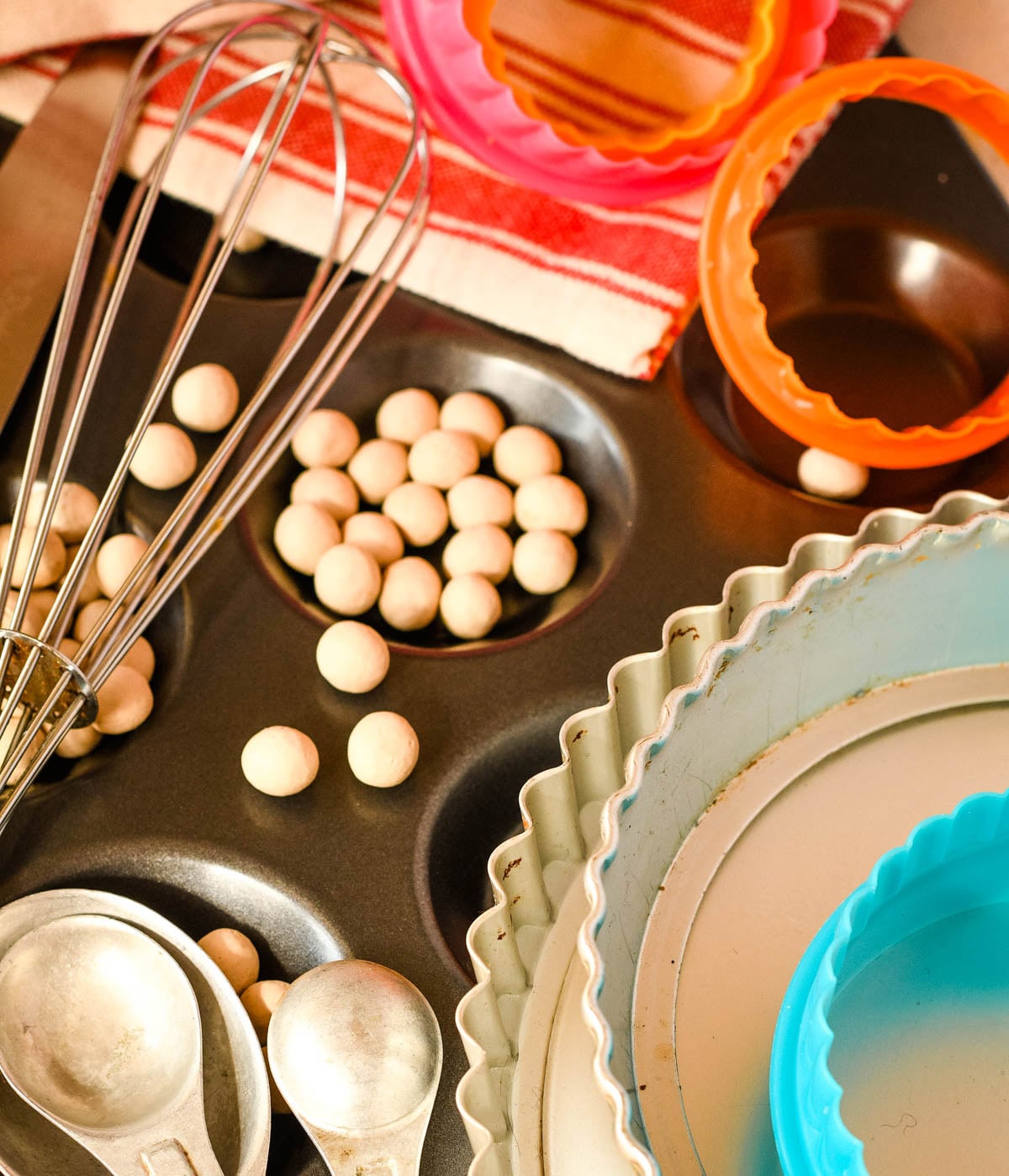 Baking tools and supplies including a whisk, measuring spoons, tart tins, silicone cutters, and small baking decorations.