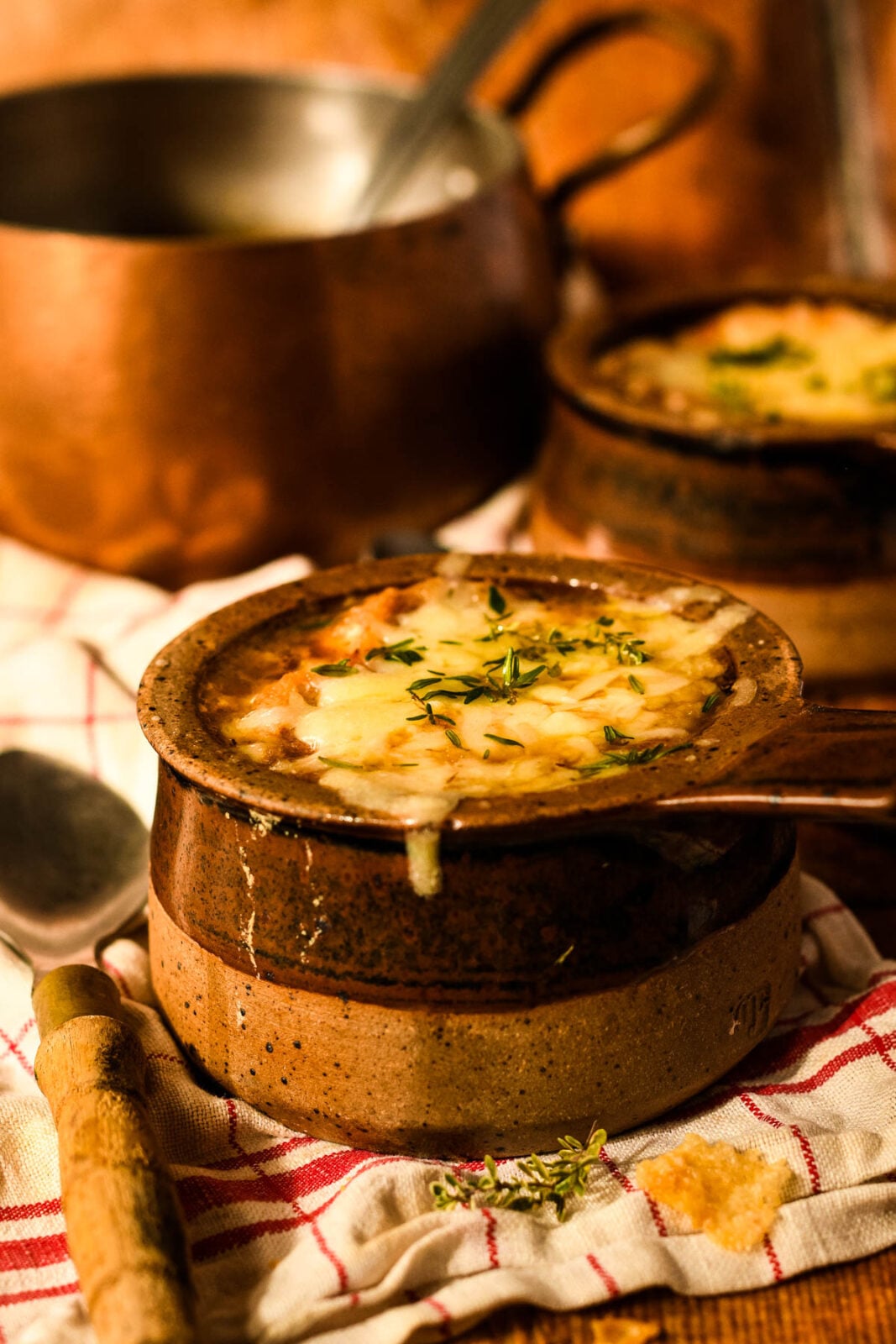 bowl of onion soup with copper pan begind