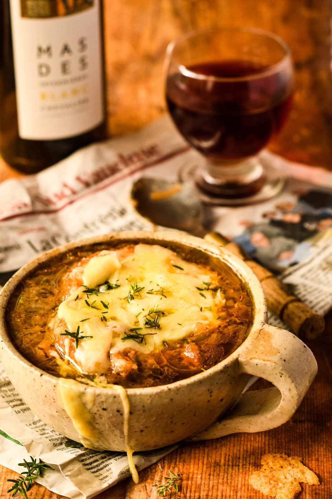 french onion soup with wine and glass behind